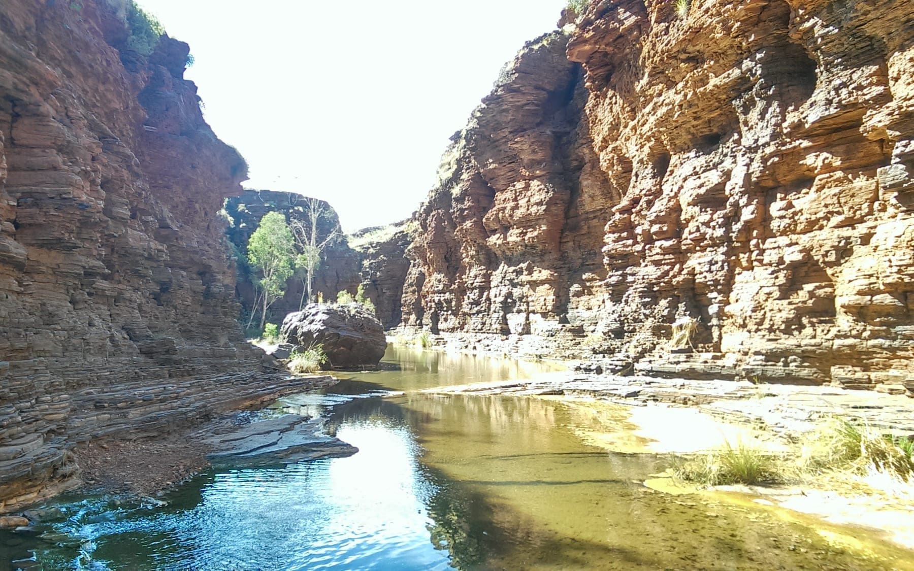 A deep red gorge in Karijini National Park with a waterhole at its base